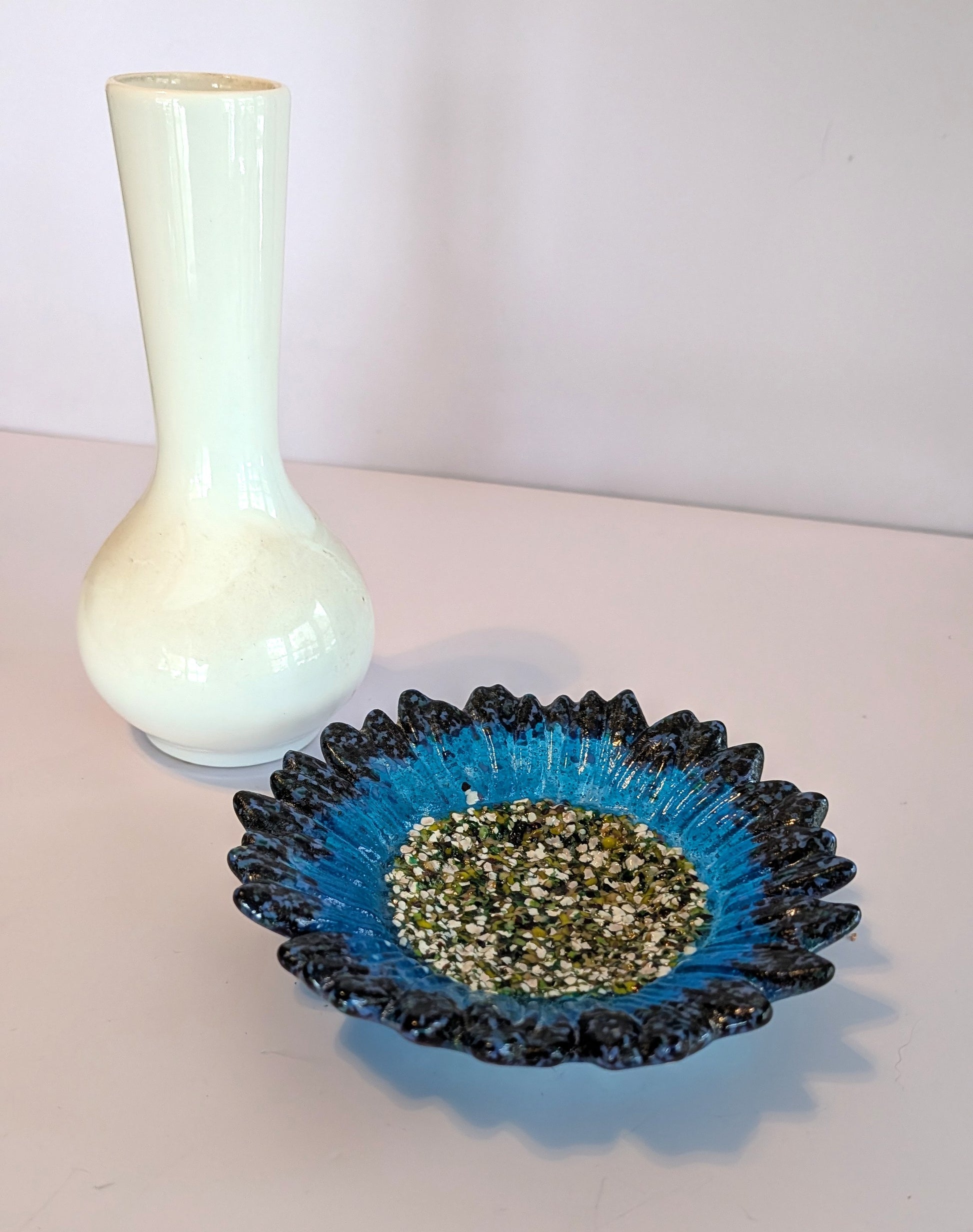 White vase and blue glass dish with decorative interior on a light surface